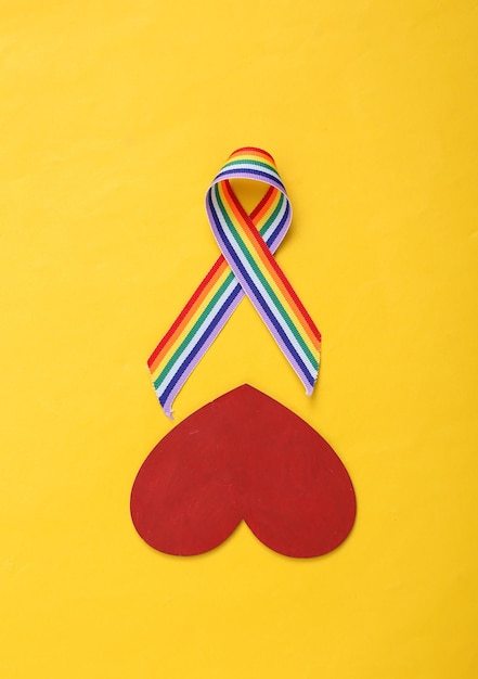 Heart and LGBT rainbow ribbon pride tape symbol on yellow background Top view