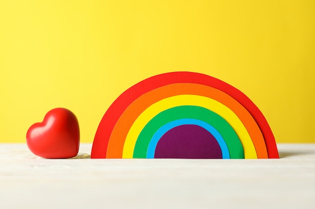 Сердце и радуга ЛГБТ на белом столе против желтого
