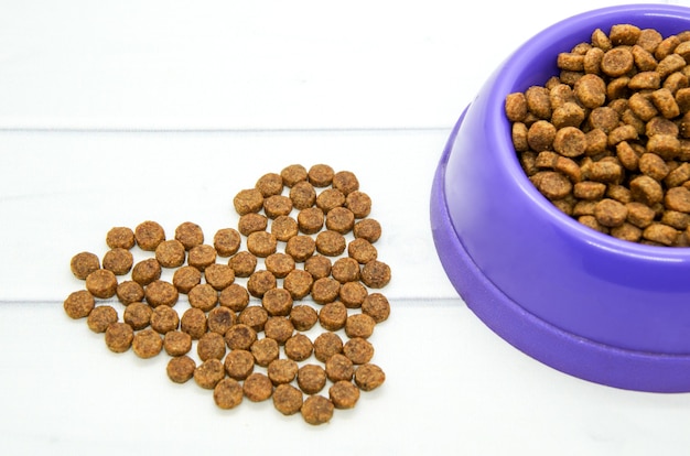 Heart lined with dry animal food and plastic bowl filled with food.