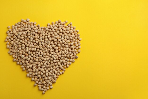 Heart made of chickpea on yellow background