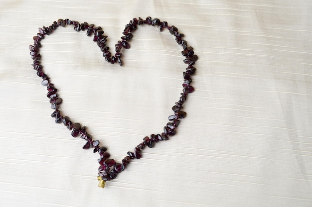 Heart made of female beautiful beads necklaces of brown dark stones amber against a background