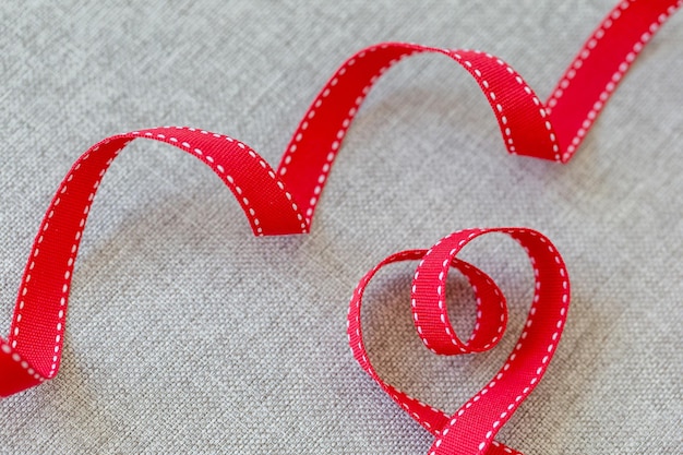 Heart made from red ribbon on linen textile with space for text valentines day concept