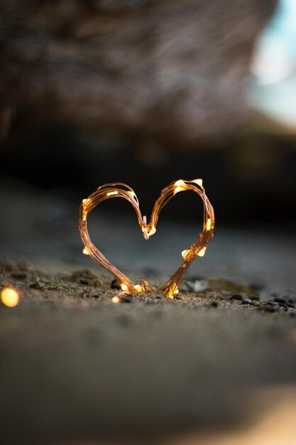 Photo a heart made of gold wire sits on the ground.