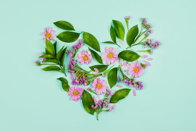 Photo heart made of leaves, violet and pink flowers.