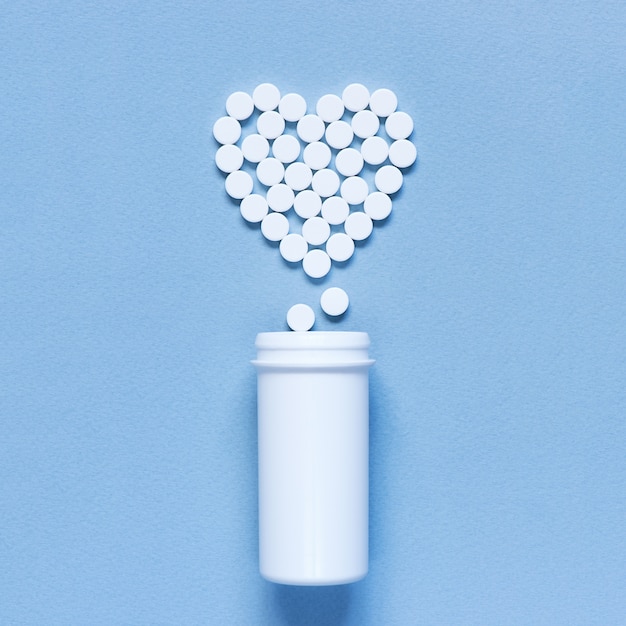 Heart made of pills on the blue textured background