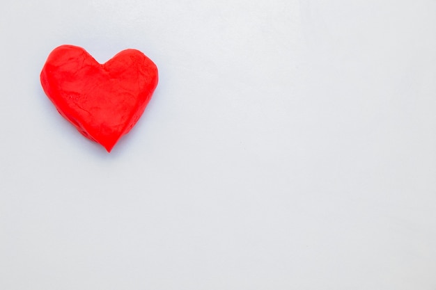 Photo a heart made of red dough for modeling lies on the side of the photo