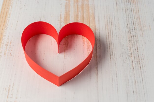 Heart made of ribbon on wooden background.