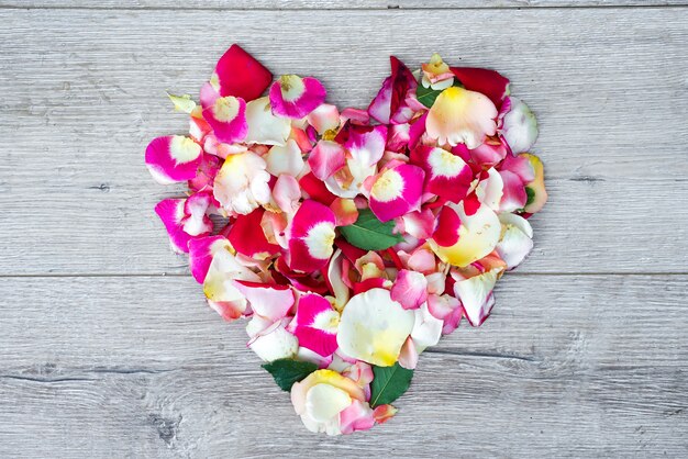 Heart made of rose flowers on wooden background for Valentines day. 