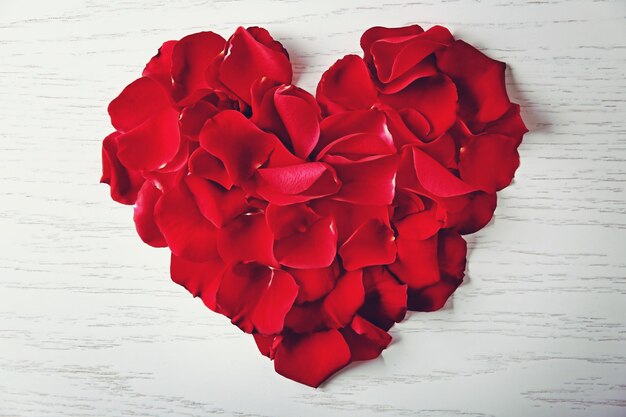 Heart made of rose petals on wooden background