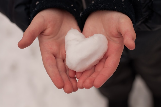 子供の手に雪でできたハート