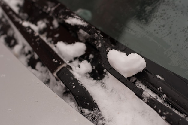 Un cuore di neve sul parabrezza accanto ai tergicristalli