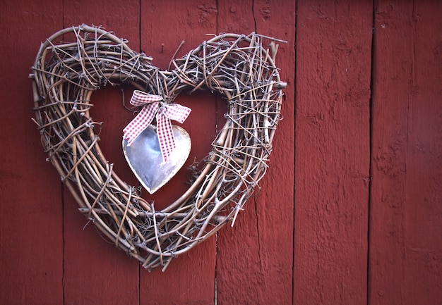 Heart made of twigs on a red wooden board