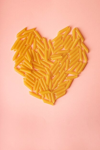 heart made with pasta on pink background