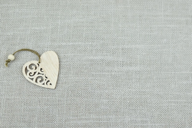 Foto cuore in legno su fondo grigio. sfondo trama beige. tela di cotone naturale.