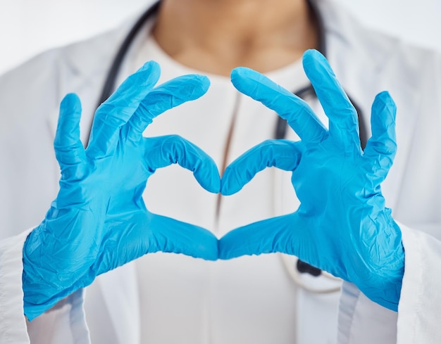 Heart medical and doctor with hands for support love and healthcare while working at a hospital Medicine care and nurse with gloves and emoji sign for consultation insurance and cardiology