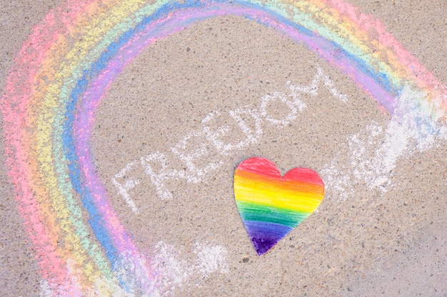 Heart painted in the colors of the lgbt community, the inscription freedom and a rainbow drawn on the asphalt with chalk, the symbol of the lgbt community