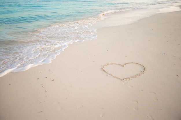 Heart painted in white sand on a tropical beach