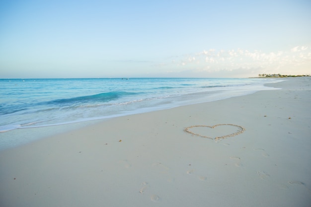 熱帯のビーチの白い砂に描かれた心