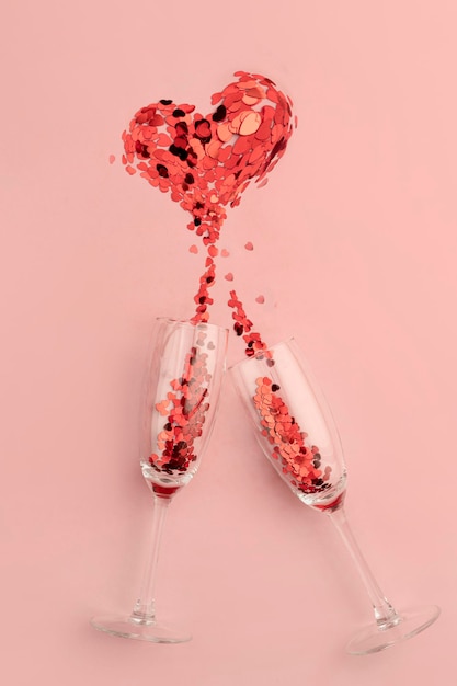 Сердце розового конфетти брызги шампанского над бокалами розовые валентинки брызги шампанского