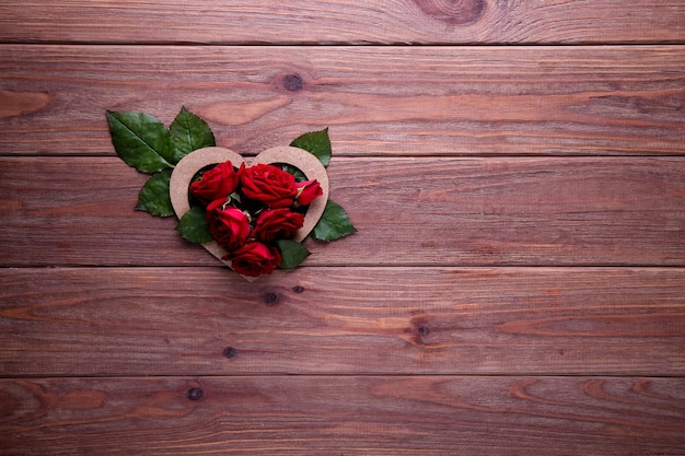 Heart of red roses on a wooden background with place for text