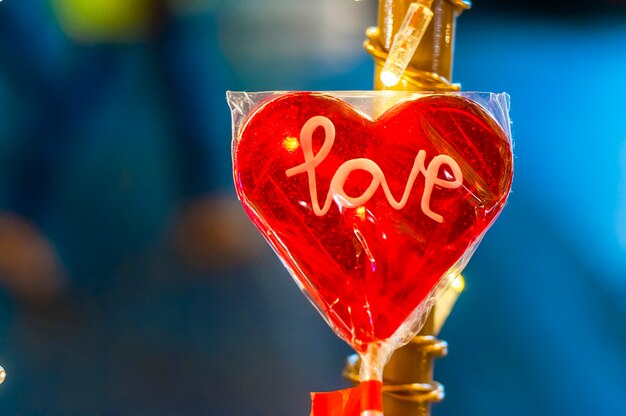 Foto cuore a forma di cuore lecca lecca, cuore di san valentino, giorno di san valentino. decorazioni natalizie - lollipop a forma di cuore, su sfondo bokeh dorato sfocato brillante.