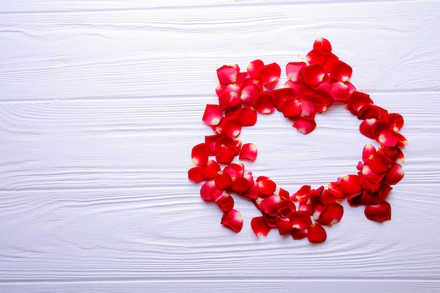 Heart of rose petals on a wooden background with place for text