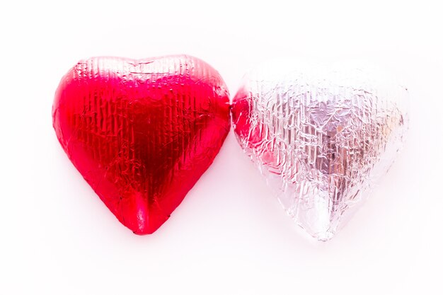 Шоколадные конфеты в форме сердца, завернутые в разноцветную фольгу на День святого Валентина.
