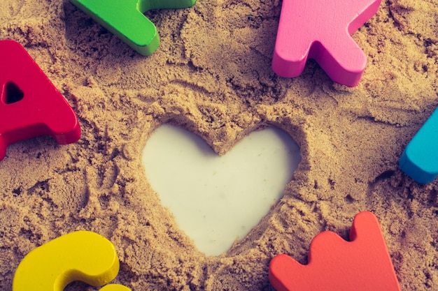 Foto a forma di cuore e lettere colorate poste sulla sabbia