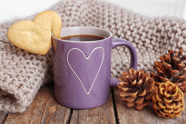 Heart shape cookie on cup of coffee on wooden table closeup