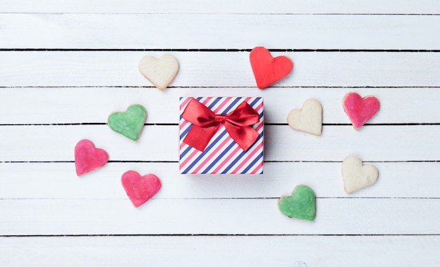 Biscotti a forma di cuore e confezione regalo su fondo di legno bianco