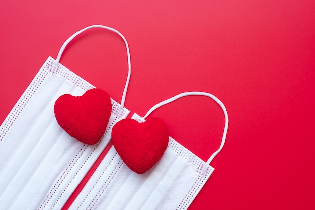 Heart shape decoration and Medical face mask on red background against Coronavirus disease infection.