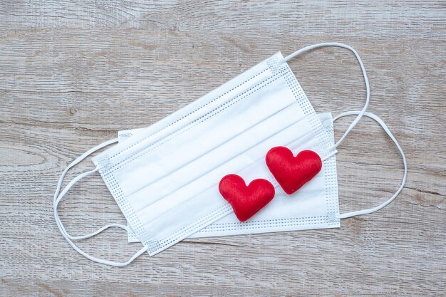 Heart shape decoration and Medical face mask on table background against Coronavirus disease infection