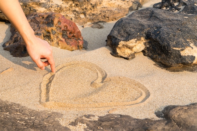 Heart shape drawing on white sand between the rock, love in rock. summer trip