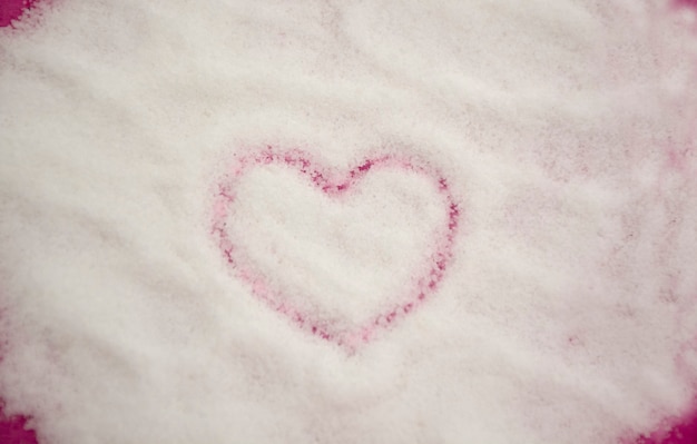 heart shape drawn on white granulated sugar background