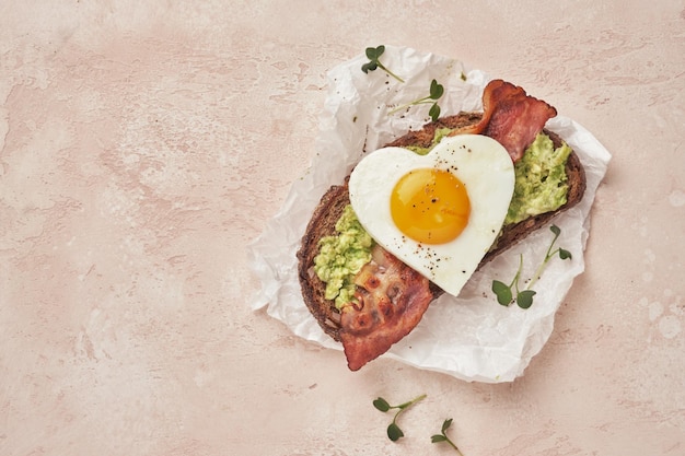 Heart shape Fried egg sandwich with avocado and bacon