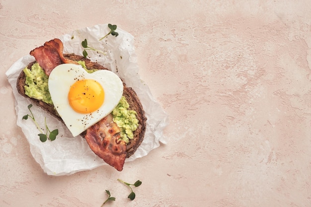 Heart shape Fried egg sandwich with avocado and bacon