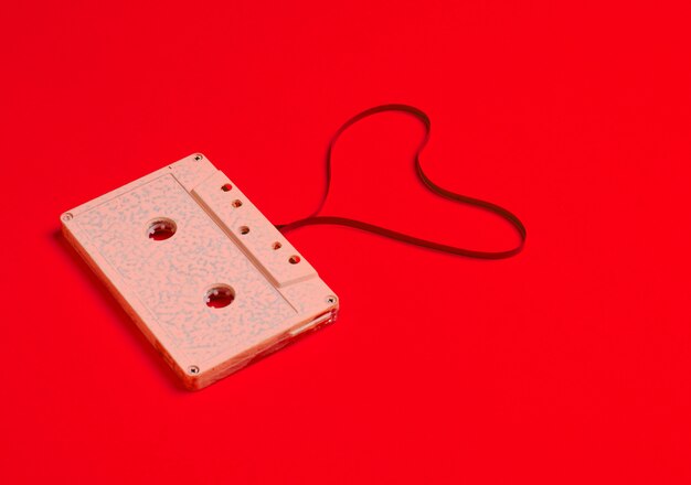 Heart shape from audio cassette tape over red paper.