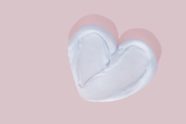 Heart shape from cream on pink background