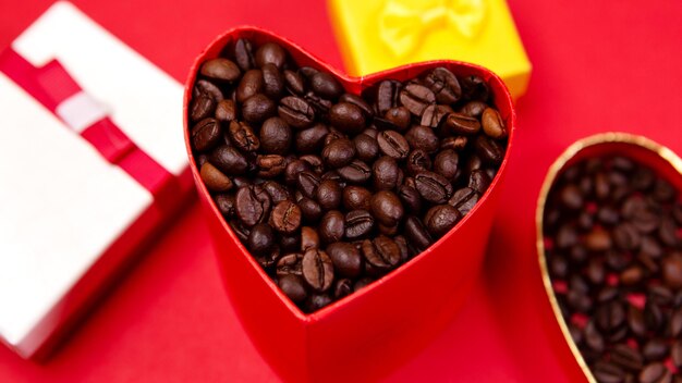 빨간색 배경에 볶은 커피 콩을 넣은 하트 모양 선물