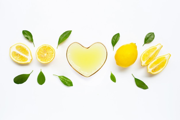 Heart shape glass of  freshly squeezed lemon juice with  fresh lemon on white