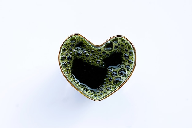 Heart shape glass of gotu kola leaves juice for health on white . Copy space