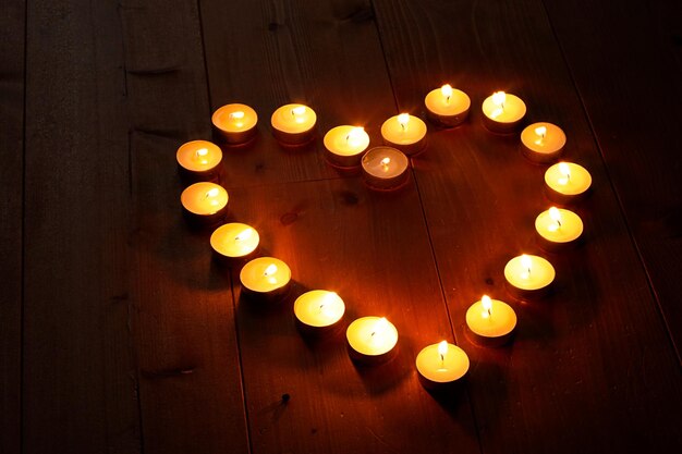 Heart shape illuminated tea lights candles on hardwood floor