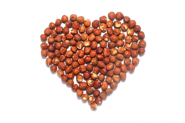 Heart shape made of nuts Brown hazelnut kernels on a white background