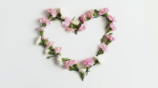 Heart shape made of pink rose and carnation on white background Flat lay top view