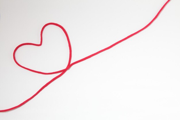 Photo heart shape made with red string on white background