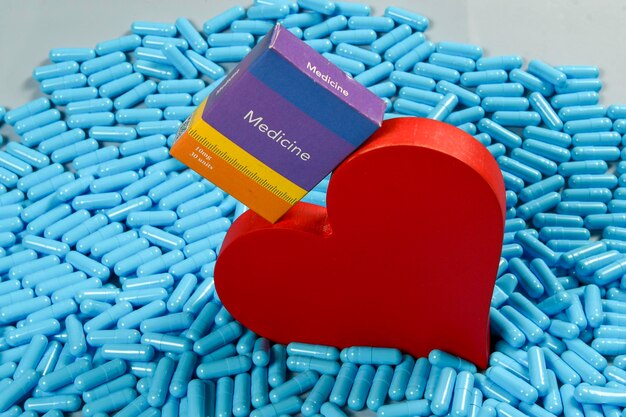 Photo heart shape and medicine capsules representing heart problems and treatment