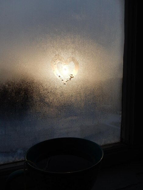 사진 해가 지는 동안 응축된 창문의 심장 모양