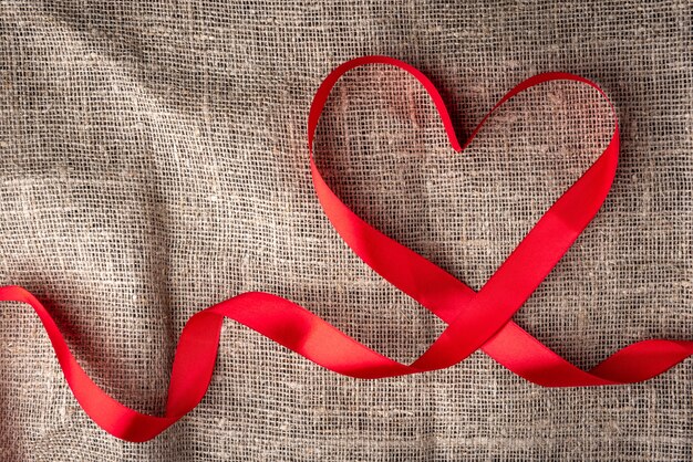 Heart shape of red ribbon on linen fabric