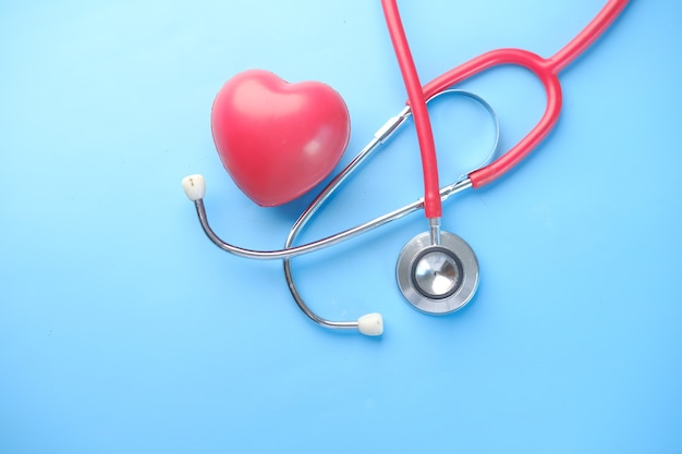 Heart shape symbol and stethoscope on blue surface