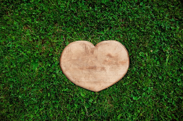 Heart shape of wood cut out in green grass background